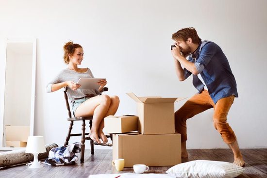 young-couple-moving-in-new-house-taking-photos-PD4QPZ5