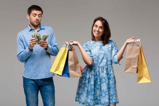 young-woman-with-purchases-man-holding-money-grey-wall (1)