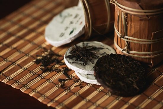 close-up-puer-tea-with-golden-toad-bamboo-mat-black-background_8353-6734