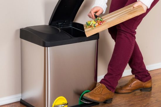 woman-throwing-wasted-food-into-steel-bin_181624-39474